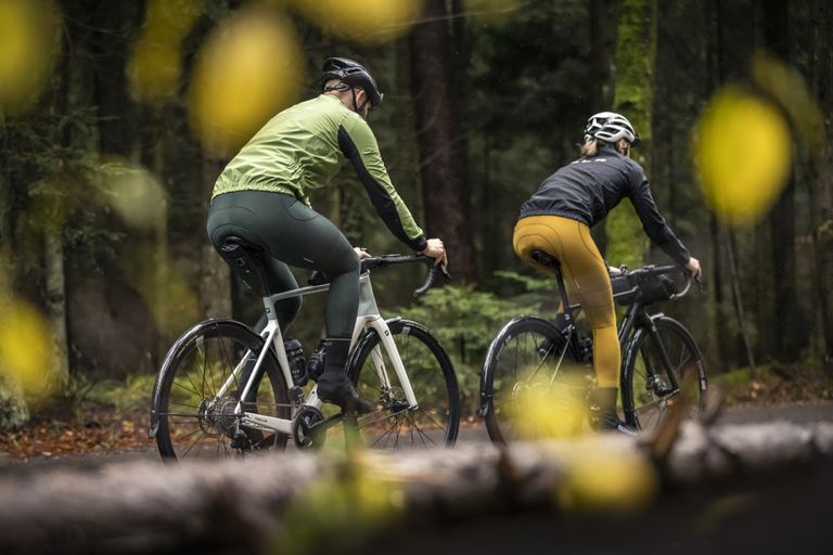 2 Personen fahren auf dem Rad durch einen Wald